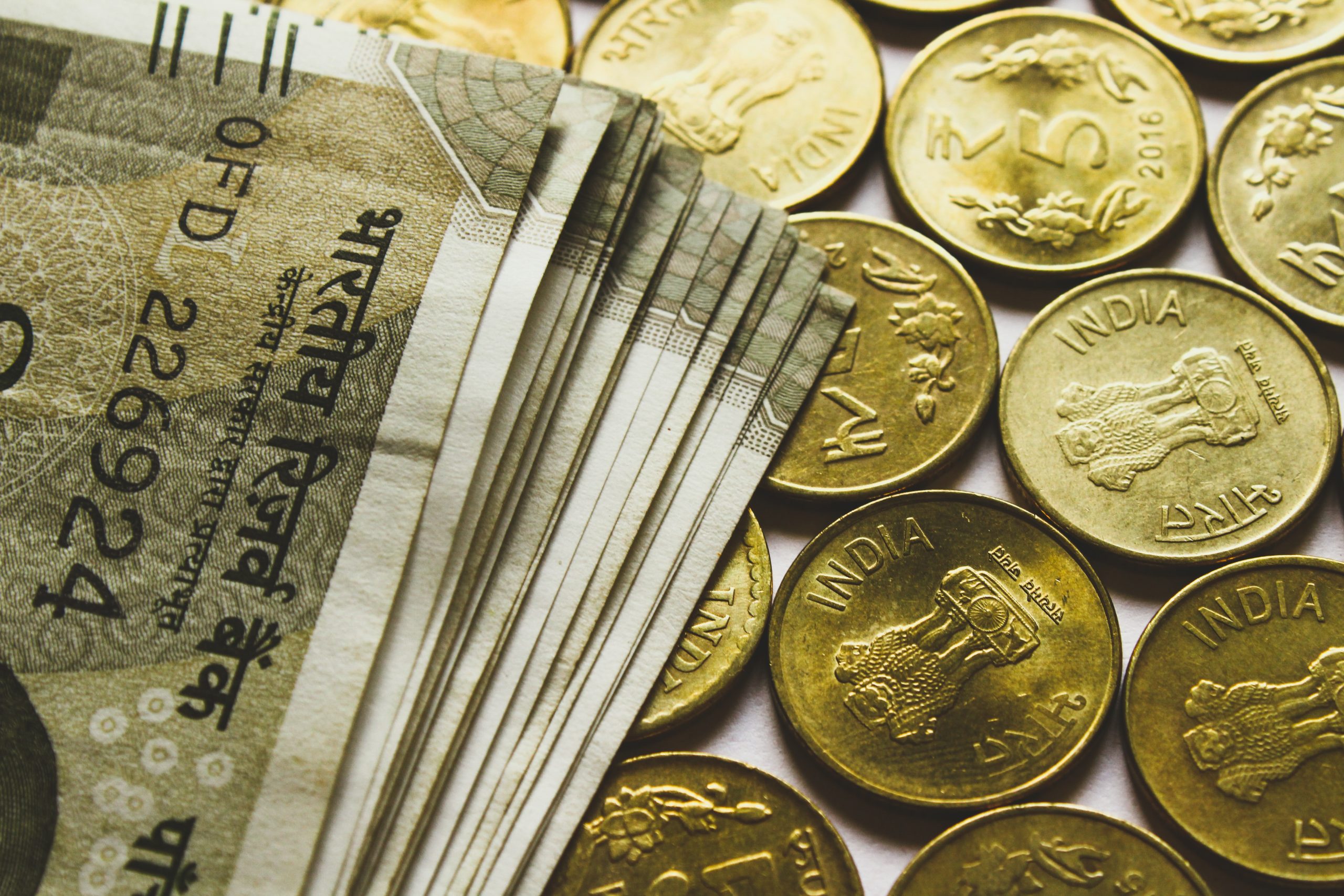 round gold-colored rupee coins and banknotes