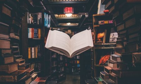 view of floating open book from stacked books in library