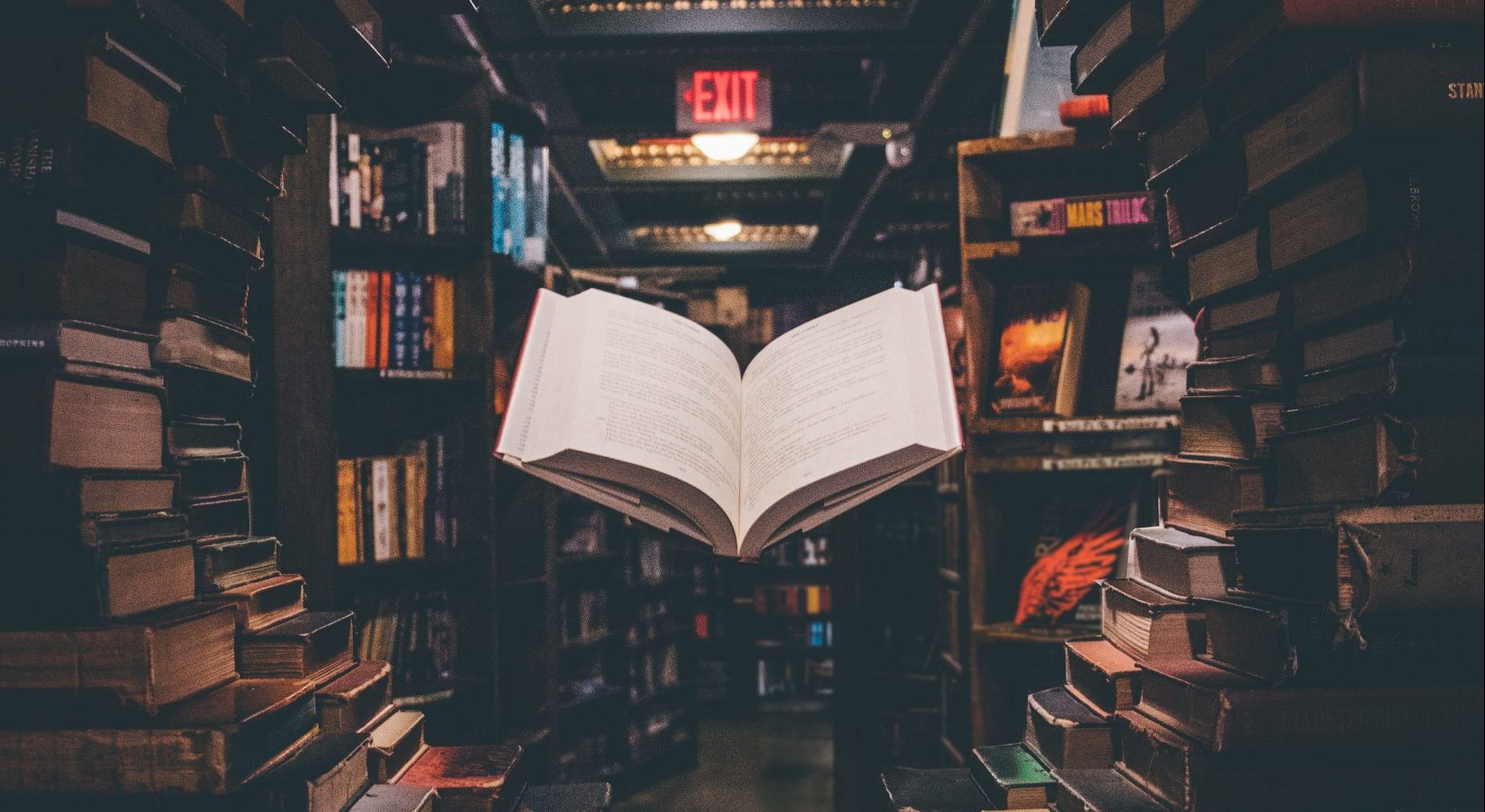 view of floating open book from stacked books in library