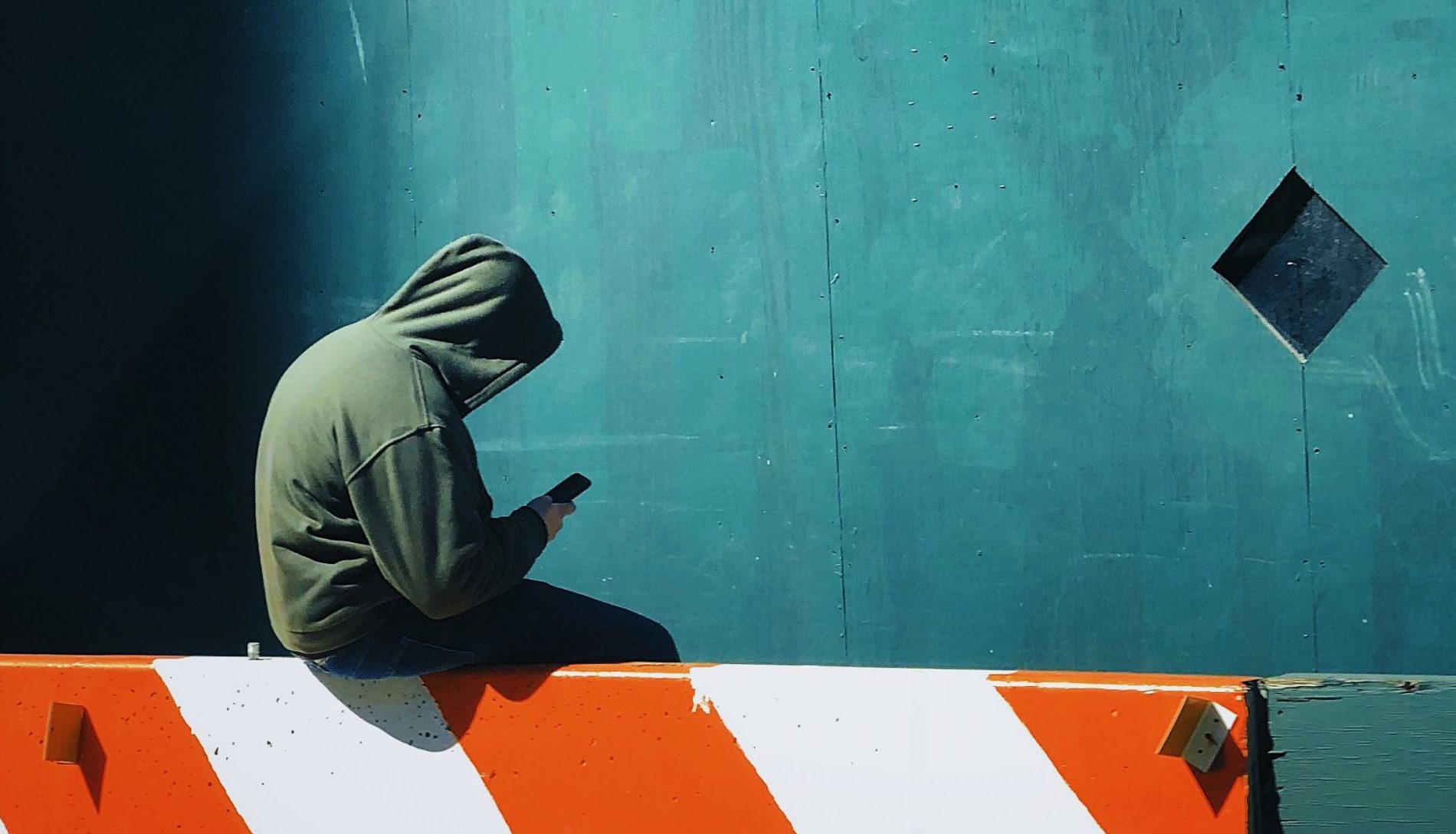 person in hooded jacket using smartphone