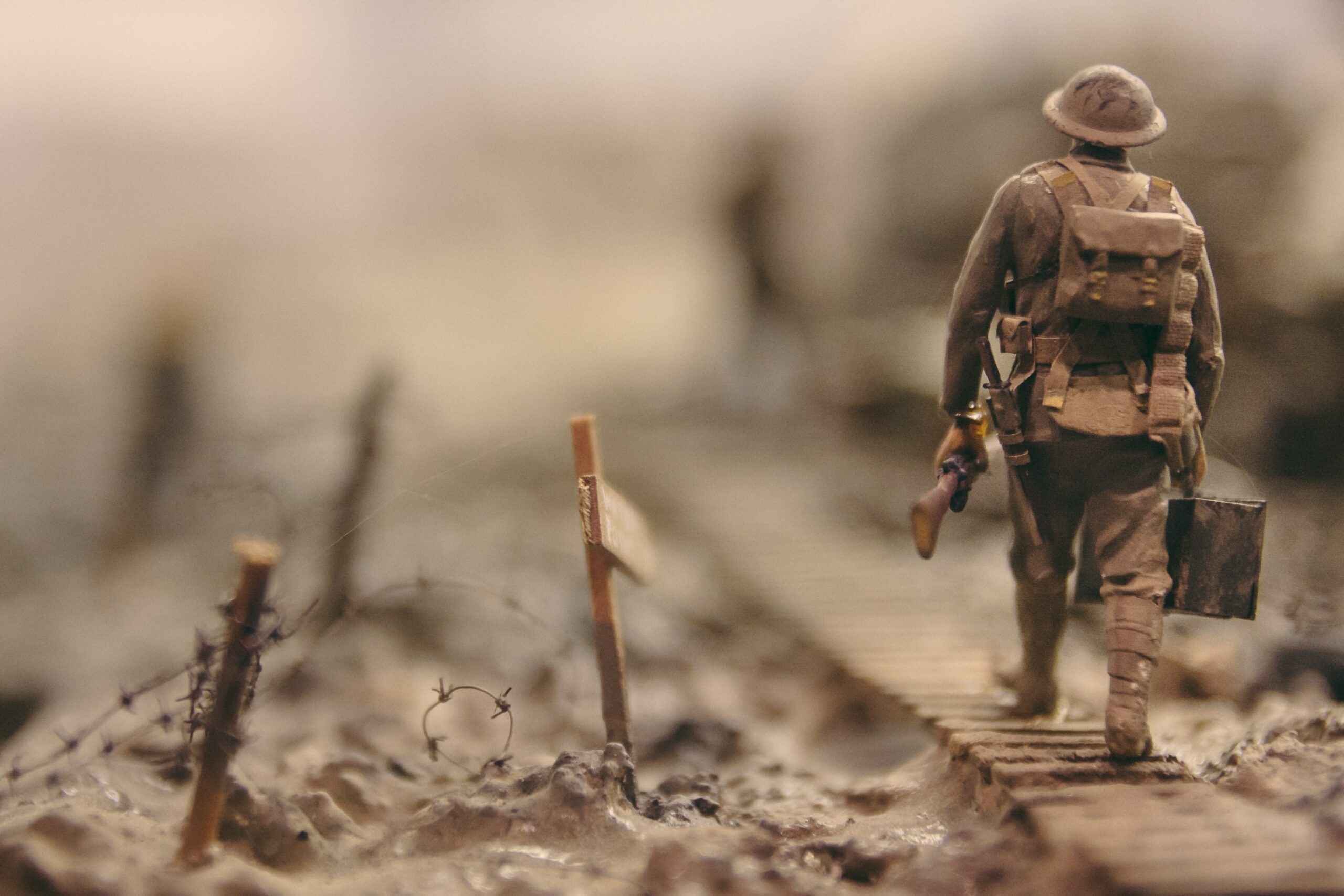 soldier walking on wooden pathway surrounded with barbwire selective focus photography