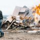 man in black jacket and blue denim jeans standing in front of bonfire