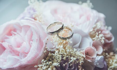 gold-colored bridal ring set on pink rose flower bouquet