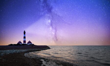 white and red lighthouse near bodies of water at night