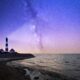 white and red lighthouse near bodies of water at night