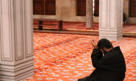 man in black robe sitting on red floor