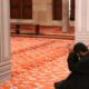 man in black robe sitting on red floor