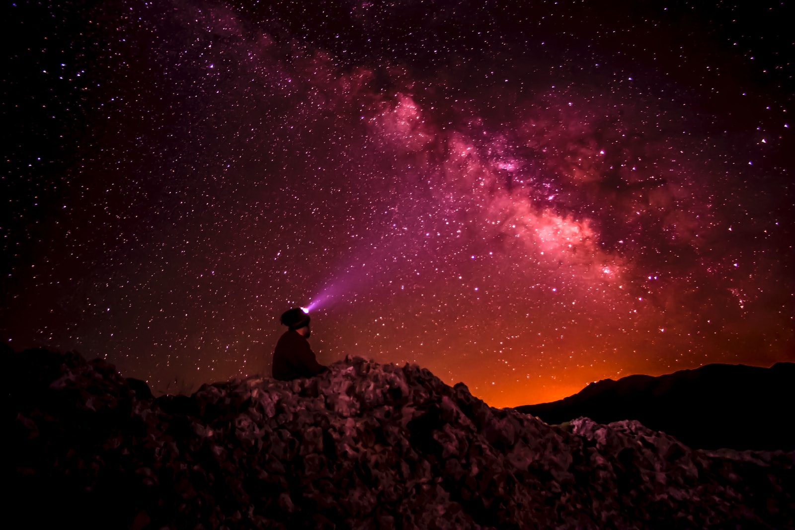 silhouette photo of person holding flashlight under milk way