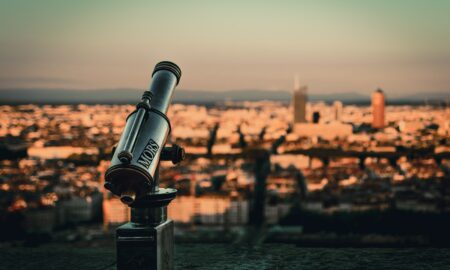 selective focus photography of telescope by cityscape during daytime