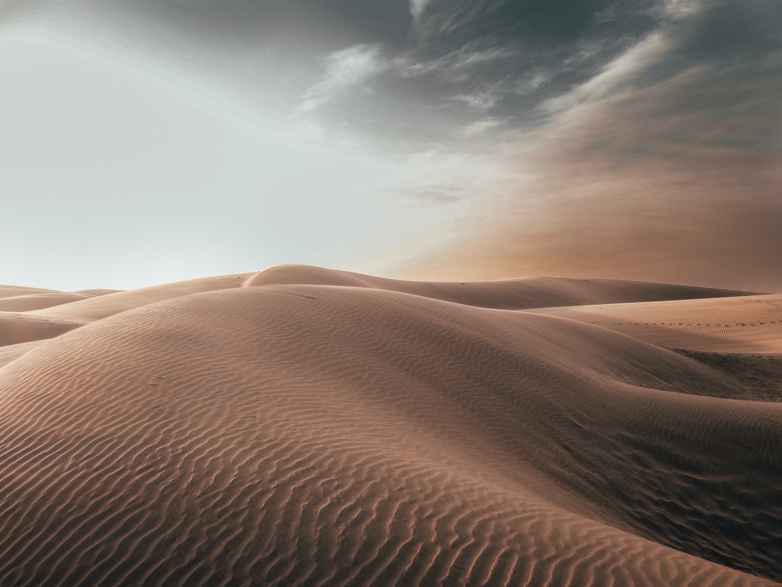 sand dunes at desert under grey cloudy sky