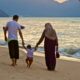 man and woman holding hands while walking on beach during daytime