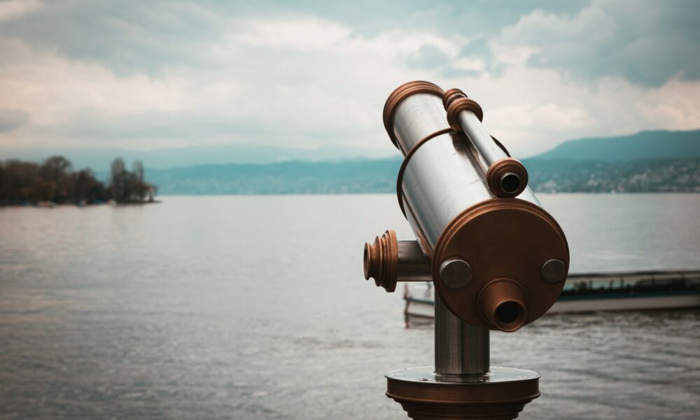 brown and silver telescope near body of water during daytime
