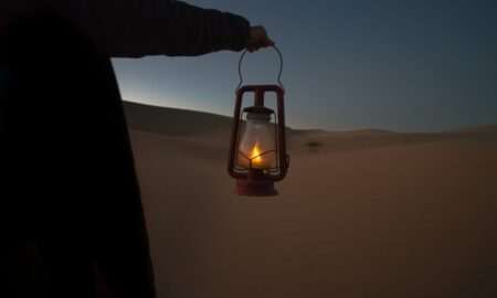 person holding red kerosene lantern