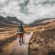 person wearing backpack walking on dirt road