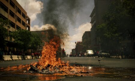 fire burning on the road with high rise buildings during daytime photography