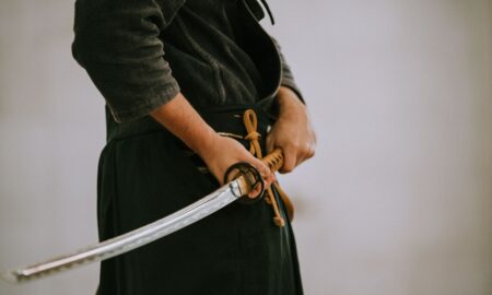 person in black long sleeve shirt and black skirt holding white leather belt