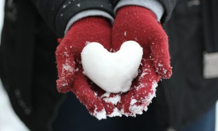 person holding heart-shaped snow