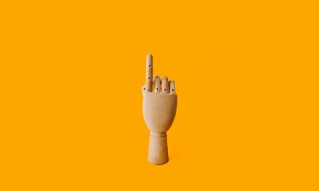 beige wooden hand sculpture with orange background