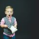 boy wearing gray vest and pink dress shirt holding book