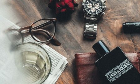 round silver watch, red rose and eyeglasses on wooden surface