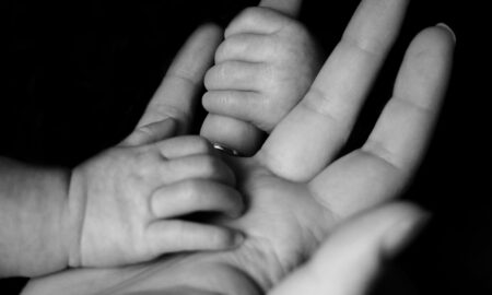 photo of baby holding person's fingers