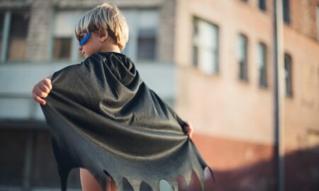 selective focus photography of boy wearing black Batman cape