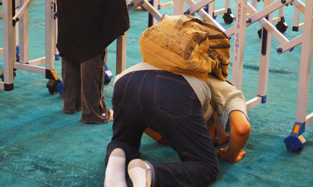 a man kneeling on the ground with a backpack on his head