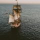 brown sailboat in beach under white sky