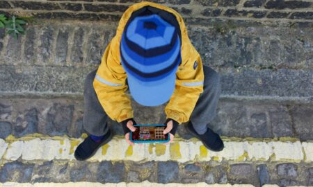 a person kneeling on the ground looking at a cell phone