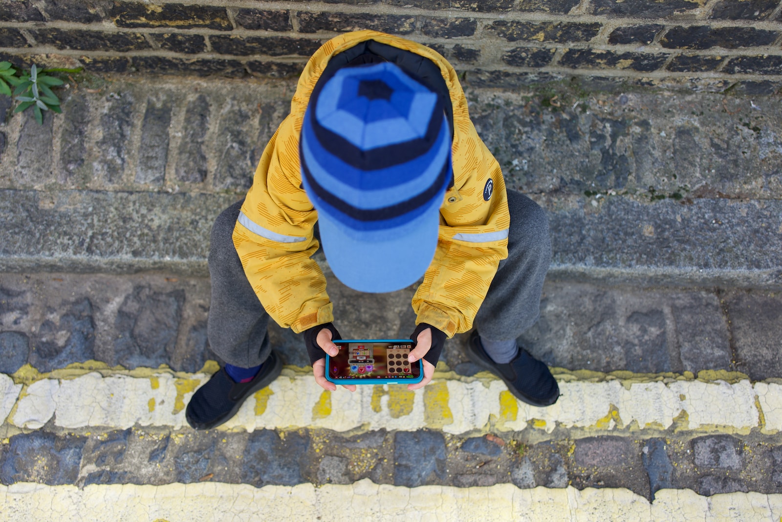 a person kneeling on the ground looking at a cell phone