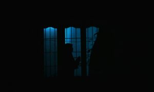 a person standing in front of a window in the dark