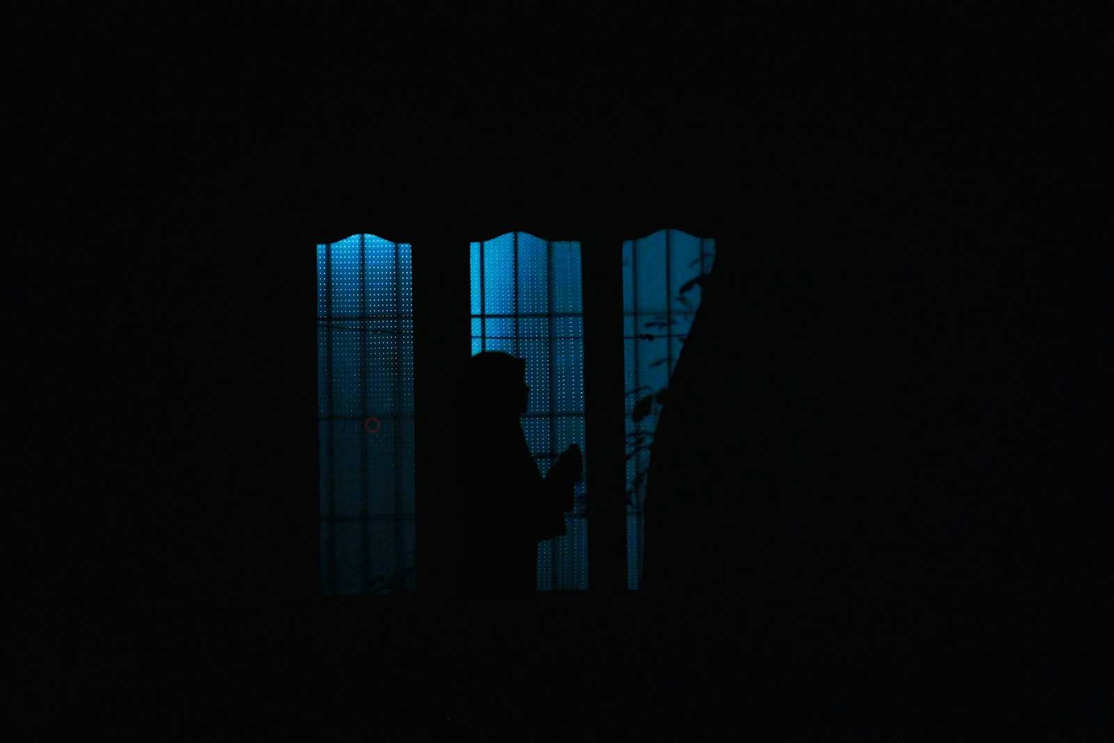 a person standing in front of a window in the dark