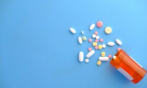 colorful pills spilling from orange bottle