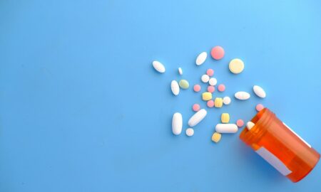 colorful pills spilling from orange bottle